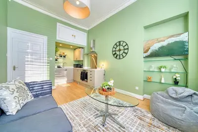 a living room with a blue couch and a glass table at 3-Bed Flat Free Parking 10 Mins to City Centre in Glasgow