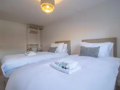 two beds in a room with white sheets at Pass the Keys Next to Braehead - Free Parking in Renfrew