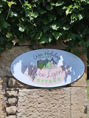 a surfboard with a house on it sitting on a wall at Wee Lyon Cottage Maybole 2 Bedroom Sleeps 4 in Maybole