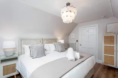 a bedroom with a large white bed and a chandelier at No36 South Beach - Donnini Apartments in Troon