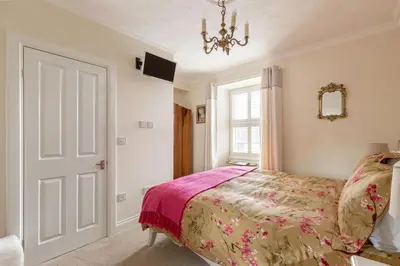 a bedroom with a bed and a window and a chandelier at Persie Croft Bed & Breakfast in Auchterarder