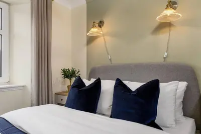 a bedroom with a bed with blue and white pillows at Central Cathedral Apartment in Dunblane