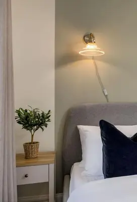 a bedroom with a bed with a lamp and a plant at Central Cathedral Apartment in Dunblane
