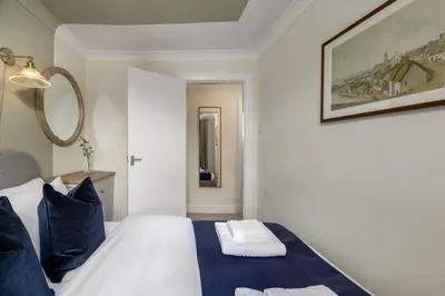 a bedroom with a white bed with blue pillows at Central Cathedral Apartment in Dunblane