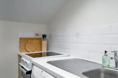 a white kitchen with a sink and a stove at Central Cathedral Apartment in Dunblane