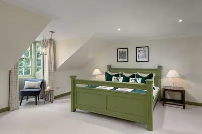 a bedroom with a green bed and a blue chair at Historic Trackside Retreat, Charming Getaway in Stirling