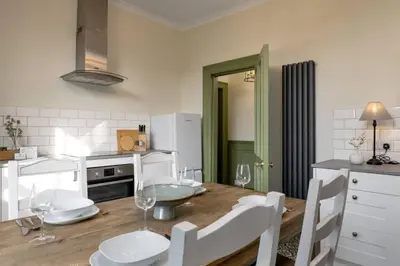 a kitchen with a wooden table with chairs and a dining room at Historic Trackside Retreat, Charming Getaway in Stirling