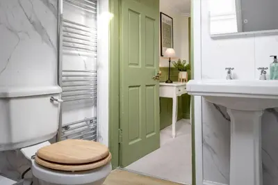 a bathroom with a green door and a toilet and a sink at Historic Trackside Retreat, Charming Getaway in Stirling