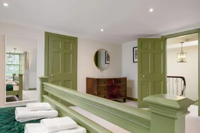 a room with green doors and a mirror at Historic Trackside Retreat, Charming Getaway in Stirling