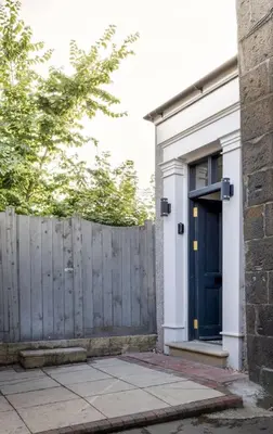 a house with a blue door and a fence at Historic Trackside Retreat, Charming Getaway in Stirling