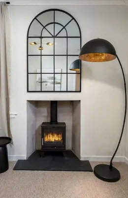 a living room with a fireplace and a black lamp at Woodland Hideaway Near Stirling in Cambusbarron
