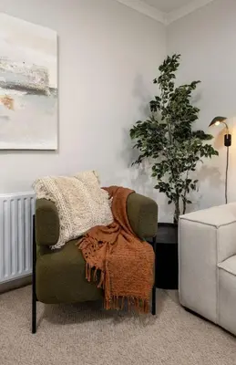 a chair with a blanket on it in a living room at Woodland Hideaway Near Stirling in Cambusbarron