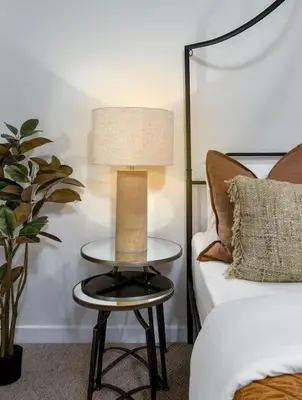 a table with a lamp on it next to a bed at Woodland Hideaway Near Stirling in Cambusbarron