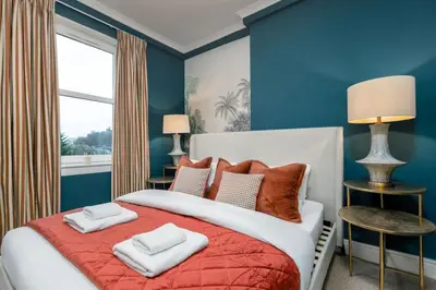 a bedroom with blue walls and a bed with two pillows at Stylish Penthouse Retreat in Stirling