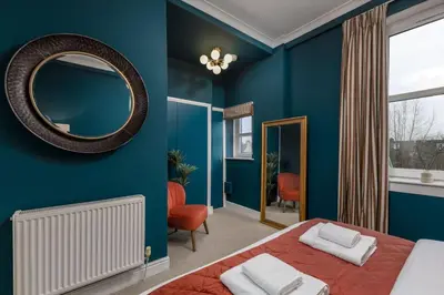 a blue bedroom with a bed and a mirror at Stylish Penthouse Retreat in Stirling
