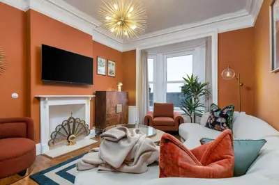 a living room with orange walls and a fireplace at Stylish Penthouse Retreat in Stirling