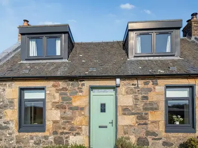 a stone house with a green door and two windows at Torr Cottage in Dalrymple