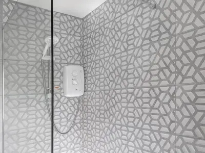 a shower in a bathroom with a patterned wall at Torr Cottage in Dalrymple