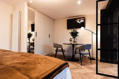 a bedroom with a bed and a table with chairs at Luxury Georgian Aparthotel by Hauss Ayr - 5mins to Beach, Town Centre! in Ayr