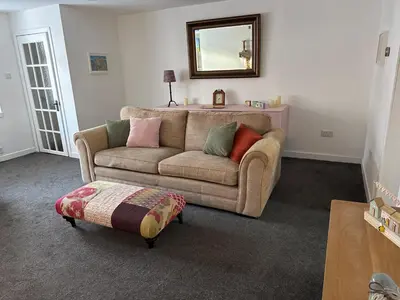 a living room with a couch and a mirror at Cosy Wee Cottage in Monkton