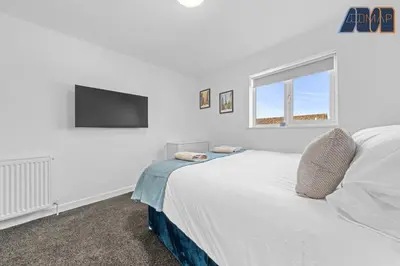 a white bedroom with a bed and a flat screen tv at 3BR Home in Kilmarnock Sleeps 6 in Kilmarnock