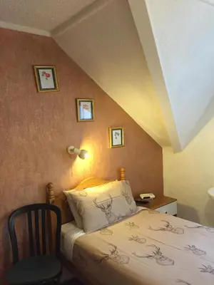 a small bedroom with a bed and a chair at Tanglin Guest House in Oban
