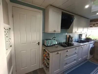 a kitchen with white cabinets and a white door at Double room in riverside apartment - B in Glasgow