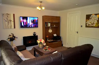 a living room with a leather couch and a tv at Double room in riverside apartment - B in Glasgow