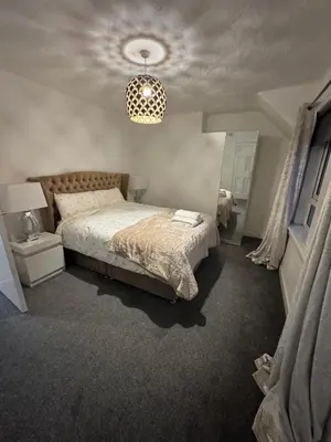 a bedroom with a bed and a chandelier at Chic & Cozy 2BR Semi-Detached in Kilmarnock