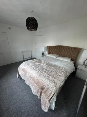 a bedroom with a large bed with a blanket on it at Chic & Cozy 2BR Semi-Detached in Kilmarnock
