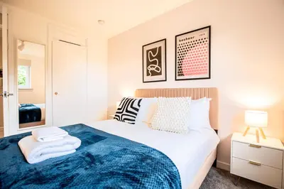 a bedroom with a bed with a blue blanket at John Neilson View - Coorie Doon in Paisley