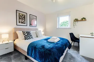 a bedroom with a bed with a blue blanket on it at John Neilson View - Coorie Doon in Paisley
