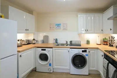 a kitchen with white cabinets and a washer and dryer at Caledonia by the Sea in Saltcoats