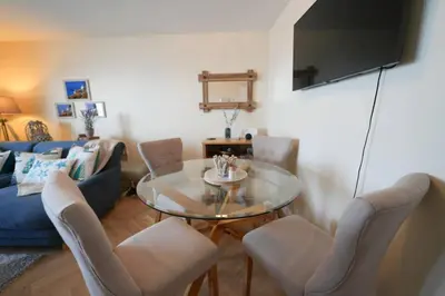 a living room with a glass table and chairs at Caledonia by the Sea in Saltcoats