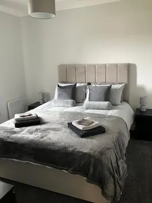 a white bedroom with a large bed with two pillows at CONTRACTOR STAYS WELCOME newly refurbished 2 bedroom apartment sleeps 5 with free SECURE parking and WiFi Fully Fitted Kitchen with Washer Dryer Weekly bedding change and hoover Long Term Stay Rate available 3 miles from City Centre in Cowlairs