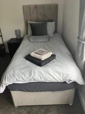 a bed with a blanket and a towel on it at CONTRACTOR STAYS WELCOME newly refurbished 2 bedroom apartment sleeps 5 with free SECURE parking and WiFi Fully Fitted Kitchen with Washer Dryer Weekly bedding change and hoover Long Term Stay Rate available 3 miles from City Centre in Cowlairs