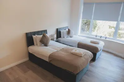 two beds in a room with a window at Stylish 3BR Home near Hampden No 264 with Free Parking in Glasgow