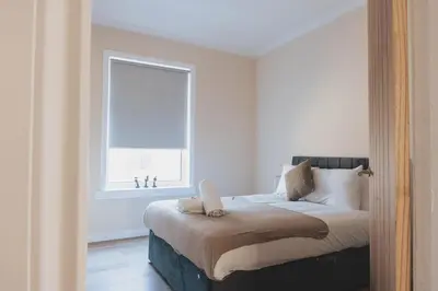 a bedroom with a large bed with a window at Stylish 3BR Home near Hampden No 264 with Free Parking in Glasgow