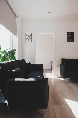 a living room with a black couch in front of a door at Stylish 3BR Stay by Hampden No 161 with Free Parking in Glasgow