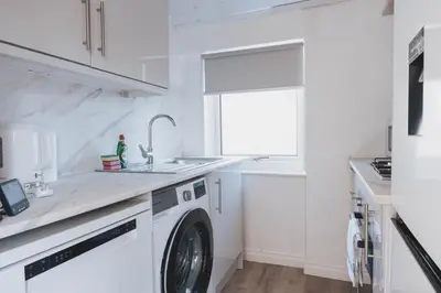a white kitchen with a washing machine and a sink at Stylish 3BR Stay by Hampden No 161 with Free Parking in Glasgow
