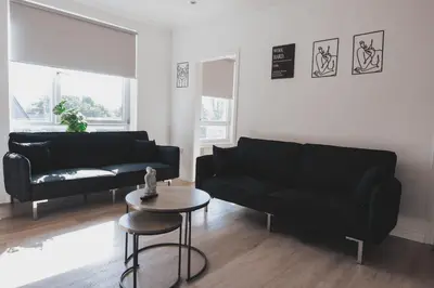 a living room with a black couch and a table at Stylish 3BR Stay by Hampden No 161 with Free Parking in Glasgow