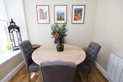 a dining room table with chairs and a vase with flowers at Stylish 3-Bed Apartment in the Heritage Quarter in Dunfermline