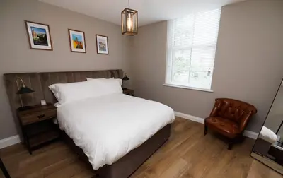 a bedroom with a bed and a chair and a window at Stylish 3-Bed Apartment in the Heritage Quarter in Dunfermline