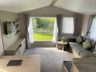 a living room with a couch and a large window at One Muirfield, Caravan at Turnberry in Turnberry