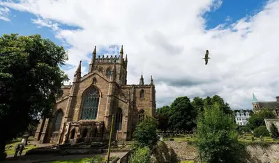 an old church with a bird flying in the sky at Stylish 1-Bed Apartment in the Heritage Quarter in Dunfermline