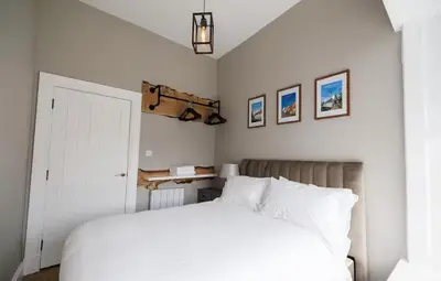 a bedroom with a white bed and some pictures on the wall at Stylish 2-Bed Apartment in the Heritage Quarter in Dunfermline