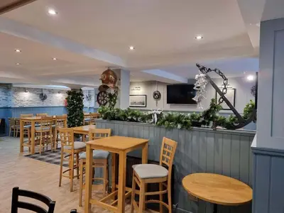 a bar with wooden tables and chairs in a restaurant at The Anchor Inn in Garelochhead