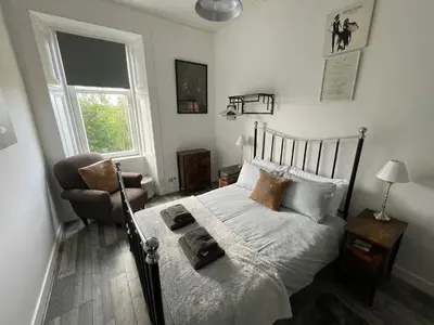 a bedroom with a bed and a chair and a window at Rothesay, Isle of Bute in Rothesay