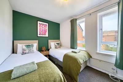 two beds in a room with green walls and windows at 2BR Flat Parking Near City and Finnieston in Glasgow