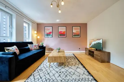 a living room with a blue couch and a tv at 2BR Flat Parking Near City and Finnieston in Glasgow